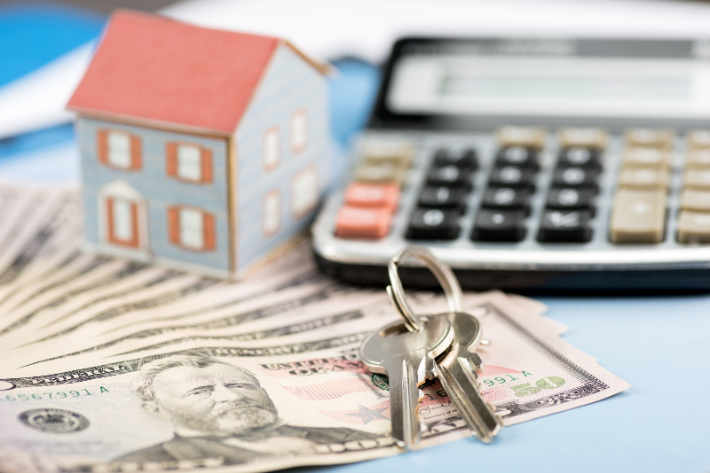calculator, money, house and keys on the table